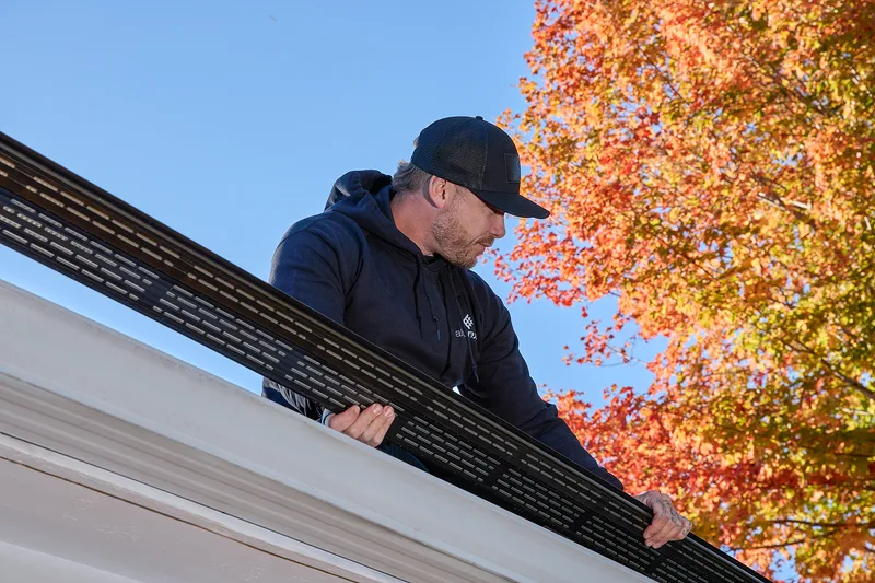 Installer carrying a new seamless aluminum gutter to the house
